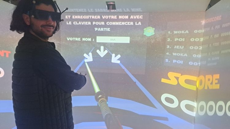 Un jeune homme muni d'un casque de réalité virtuelle en train de jouer à Space Saber, le nouveau jeu de Virtuel Concept